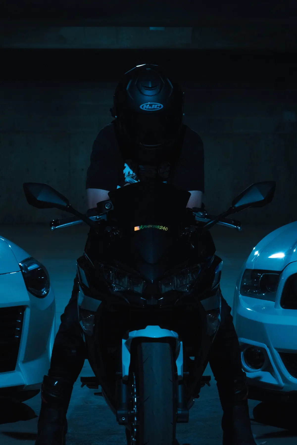 A rider in a black helmet on a sport bike between two cars