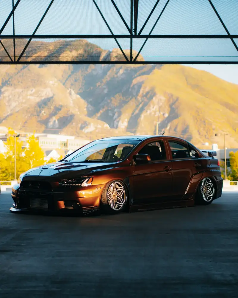 A widebody Evo parked in front of the Wasatch mountains at golden hour