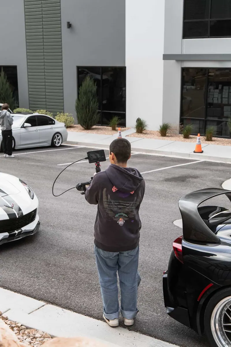 A videographer with a gimbal filming cars at a meet